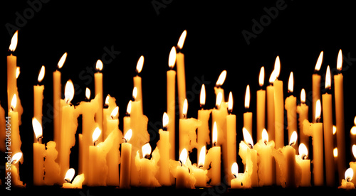 Yellow wax church candels burning in the dark. Copy space for te