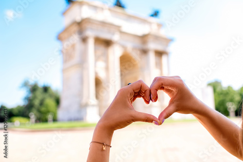 Photography Hands in form of the heart on the triumphal arch backround in Milan
