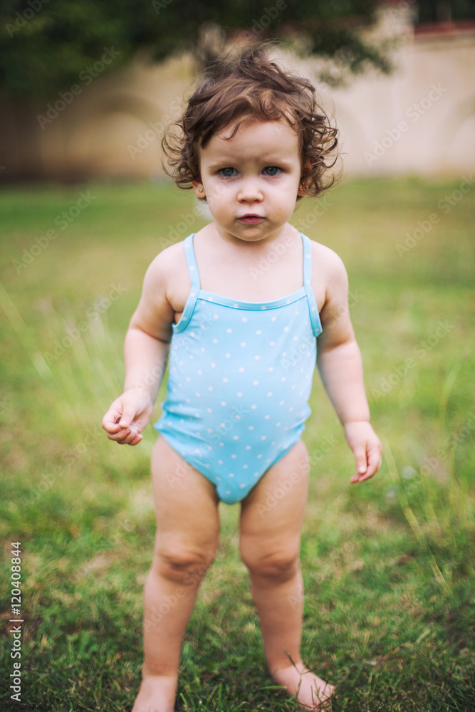 Baby in swimming suit standing in grass Baby in swimming suit standing in grass