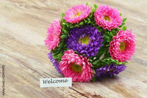 Welcome card with colorful daisy flower bouquet on wooden surface 