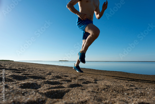 молодой мужчина бегает по пляжу летом photo