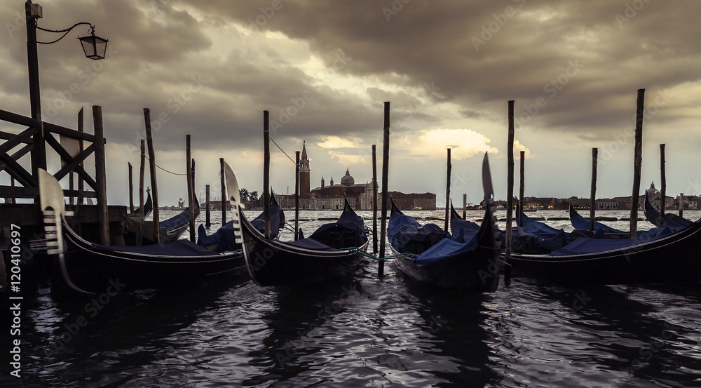 Fototapeta premium Saint Giorgio Maggiore Church in sunset, view from San Marco embankment. The church with a tower on the island and gondola in the foreground . Venice, Italy. Beautiful sunset sky in the background.
