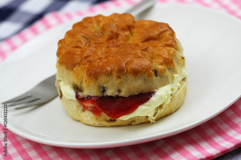 Home made English scone with traditional clotted cream and strawberry jam on white plate, closeup
Home made English scone with traditional clotted cream and strawberry jam on white plate, closeup