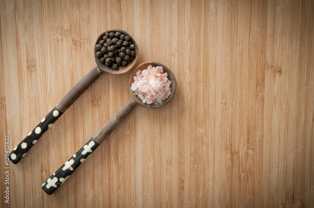 Salt and pepper seasonings of pepper corns and rock salt on wood