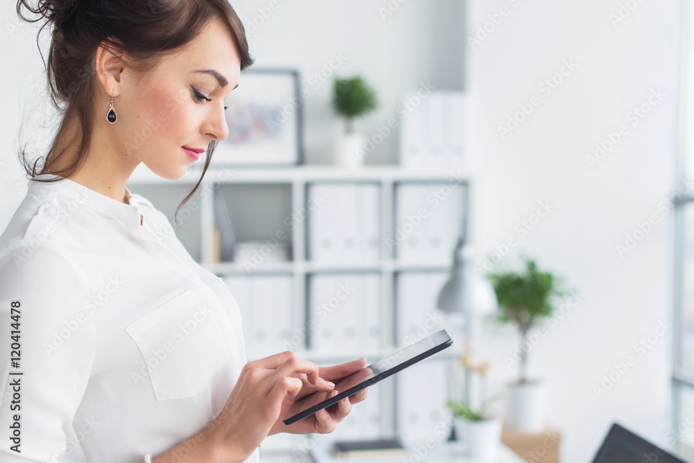 Portrait of an office manager holding her tablet, typing, using wi-fi internet and applications touching the pda screen. Portrait of an office manager holding her tablet, typing, using wi-fi internet and applications touching the pda screen.