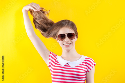 pretty girl in sunglasses posing on a yellow background. Bright stock photos. Positive human emotions