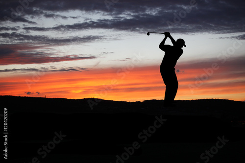 Golfer playing golf during sunset at competition event