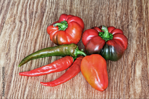 Different kinds of sweet and hot chili peppers on wooden background.