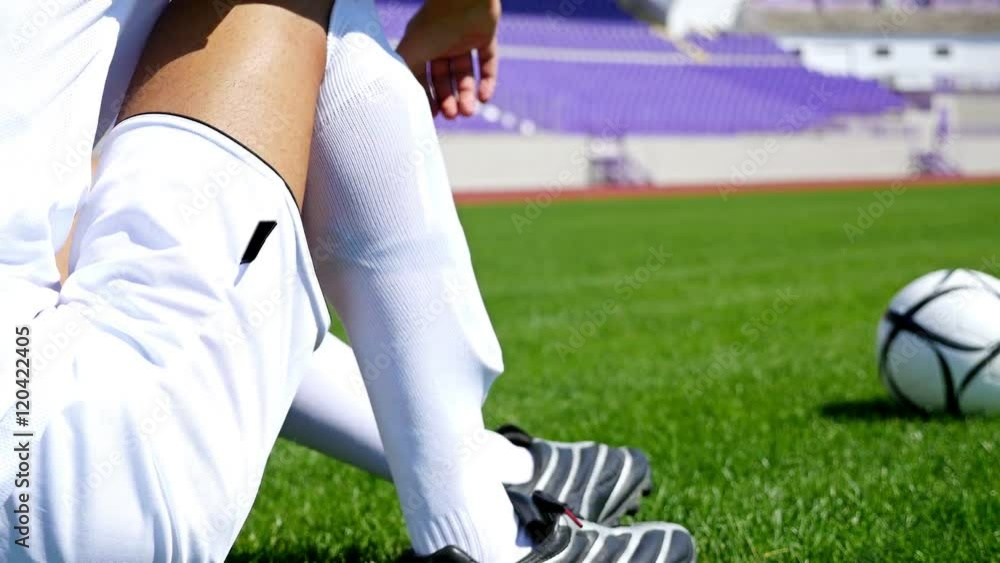 Footballer in white outfit adjusting his socks on the field Stock Video