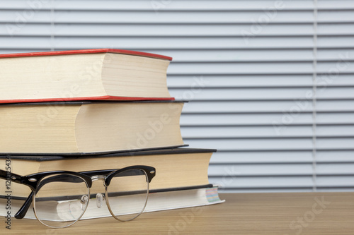 Stack of books on a table with eye glasses