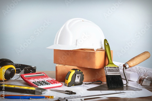 Construction blueprints with tools and helmet on light background © Africa Studio