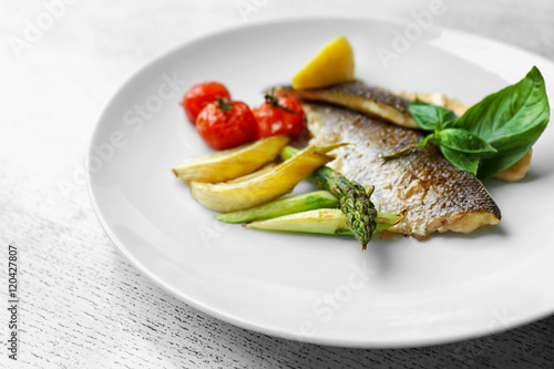 Grilled fish with vegetables on white plate