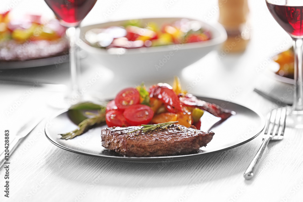 Tasty steak with fried vegetables on dinner table Tasty steak with fried vegetables on dinner table