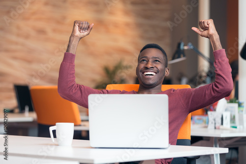 Happy smiling successful African American businessman in a modern startup office indoors