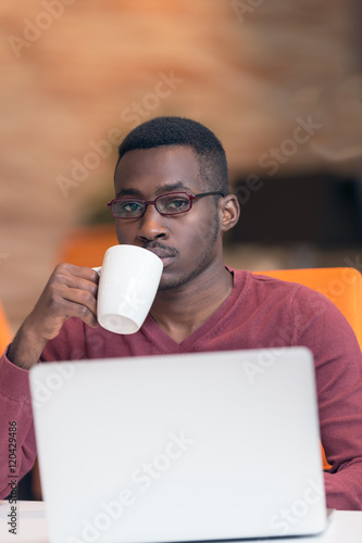 Startup business with laptop. Cheerful young African businessman typing looking on laptop.