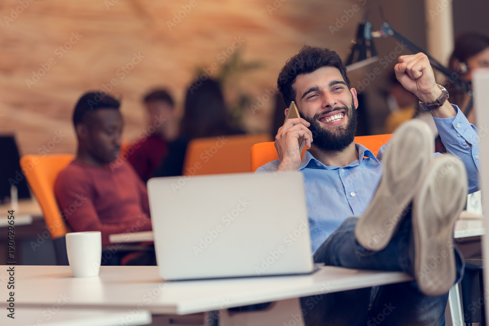 Fototapeta premium Relaxed young businessman at workplace at early morning, relaxing, at modern startup office.
