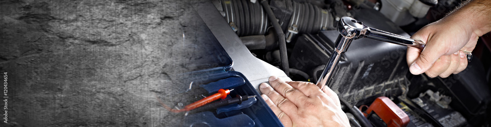 Hands of car mechanic with wrench in garage.