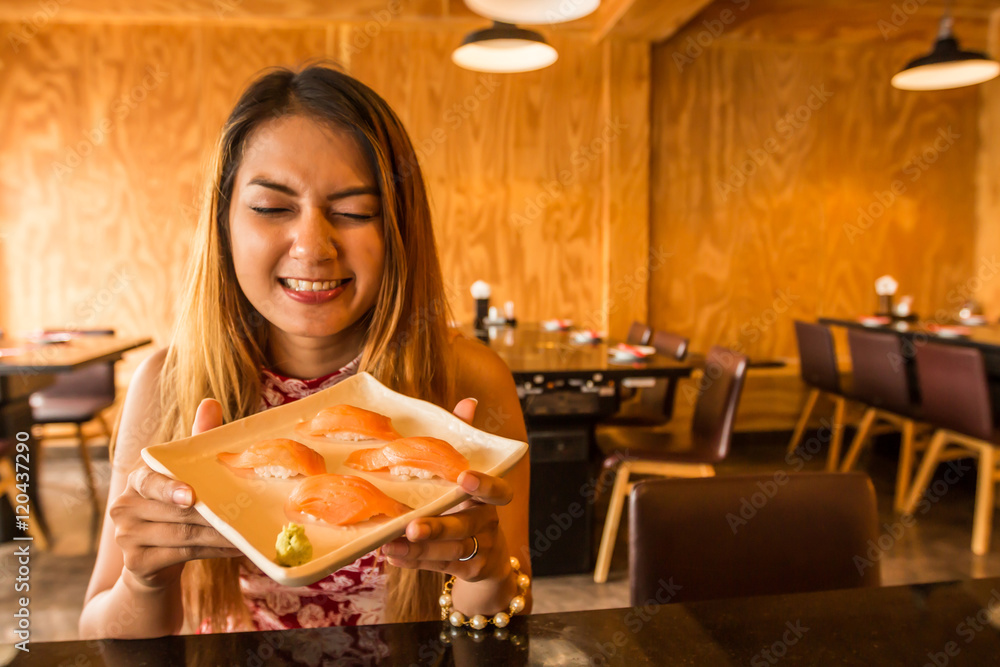 Asian woman holding plate with Salmon Sushi in Japanese restaurant. Asian woman holding plate with Salmon Sushi in Japanese restaurant.
