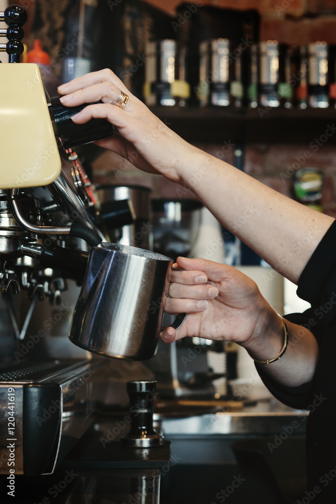 Woman barista making espresso coffee and frothing milk