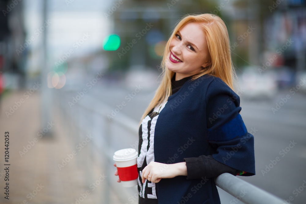 Fototapeta premium Cheerful woman in the street drinking coffee 