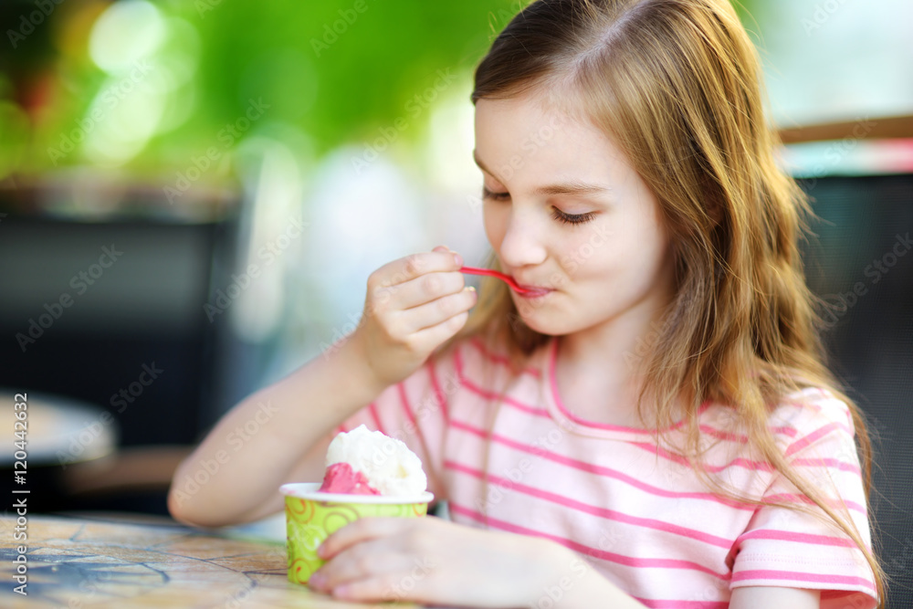 Funny little girl eating ice cream in an outdoor cafe Funny little girl eating ice cream in an outdoor cafe