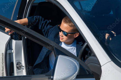 young boy in sunglasses sits in the car