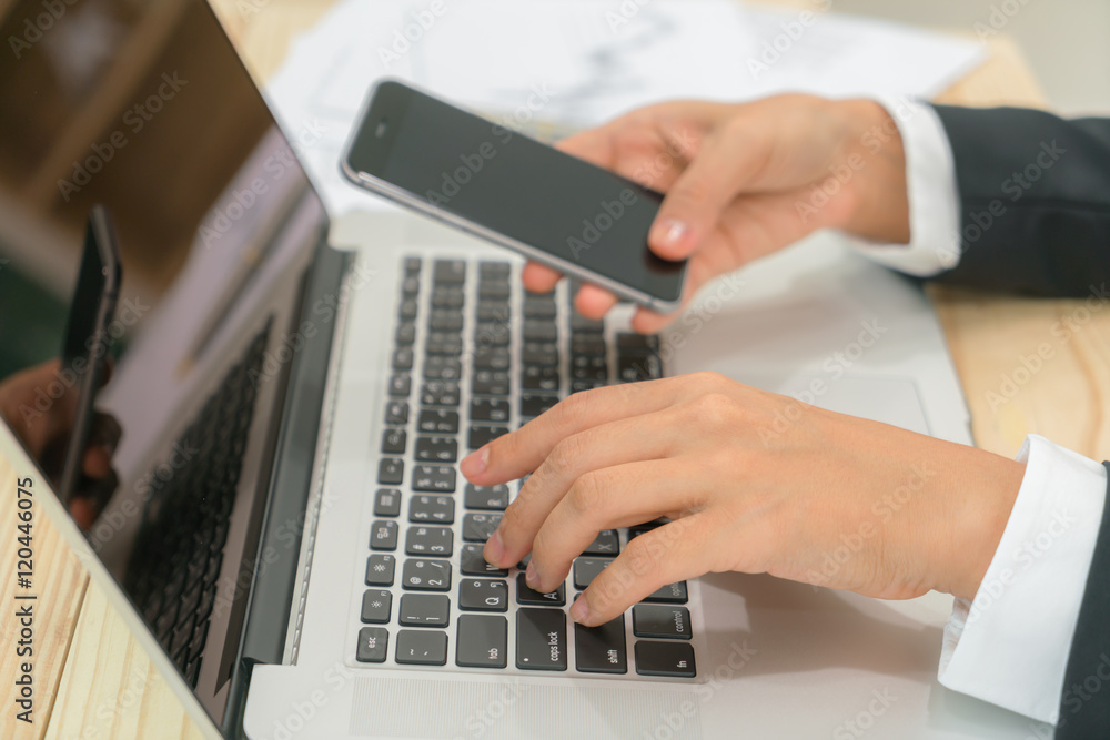 Closeup of business woman hand touch phone over laptop keyboard Closeup of business woman hand touch phone over laptop keyboard