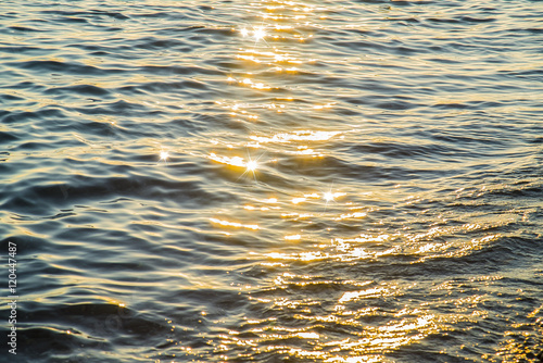 Blue sea water surface at sunset with sparks