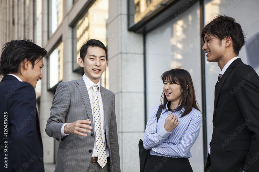 Four businessmen who are the stand talking in front of the office building Four businessmen who are the stand talking in front of the office building