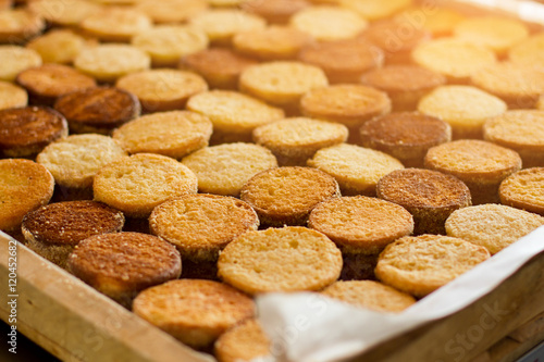 Rows of biscuits under sunlight. Yellow and brown cookies. Production of quality desserts. Shortcrust dough from the oven.