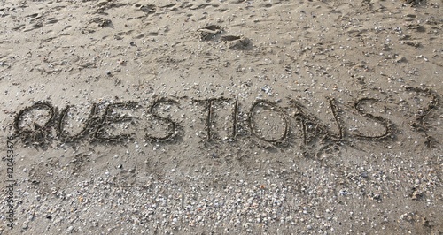 questions written on the beach sand