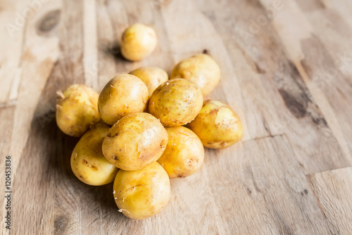 beautiful pile of small rounded whole organic potatoes with the peel isolated on an old oak cutting board with focal blur