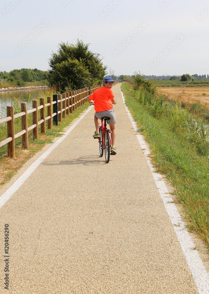 boy riding on the bike path near the lagoon of Venice boy riding on the bike path near the lagoon of Venice