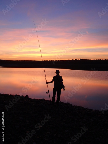 Silueta de un pescador al atardecer en un lago