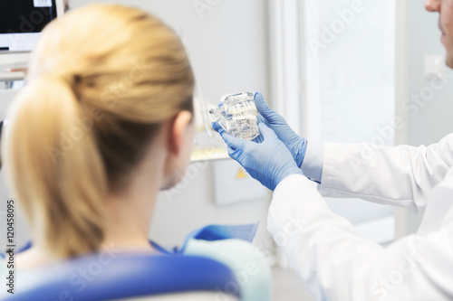 close up of dentist showing teeth model to patient