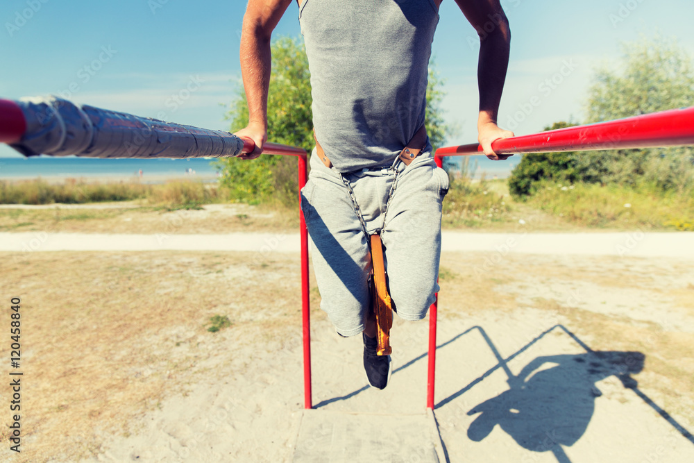 young man exercising on parallel bars outdoors young man exercising on parallel bars outdoors