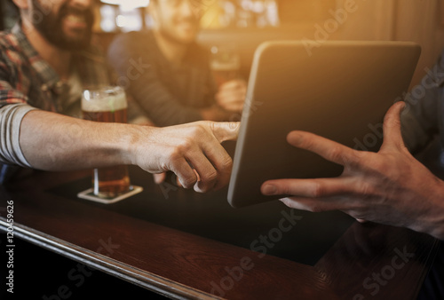 close up of men with tablet pc and beer at bar