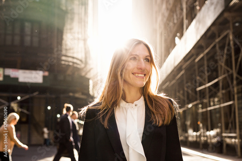 Smiling businesswoman standing on city street during sunny day photo