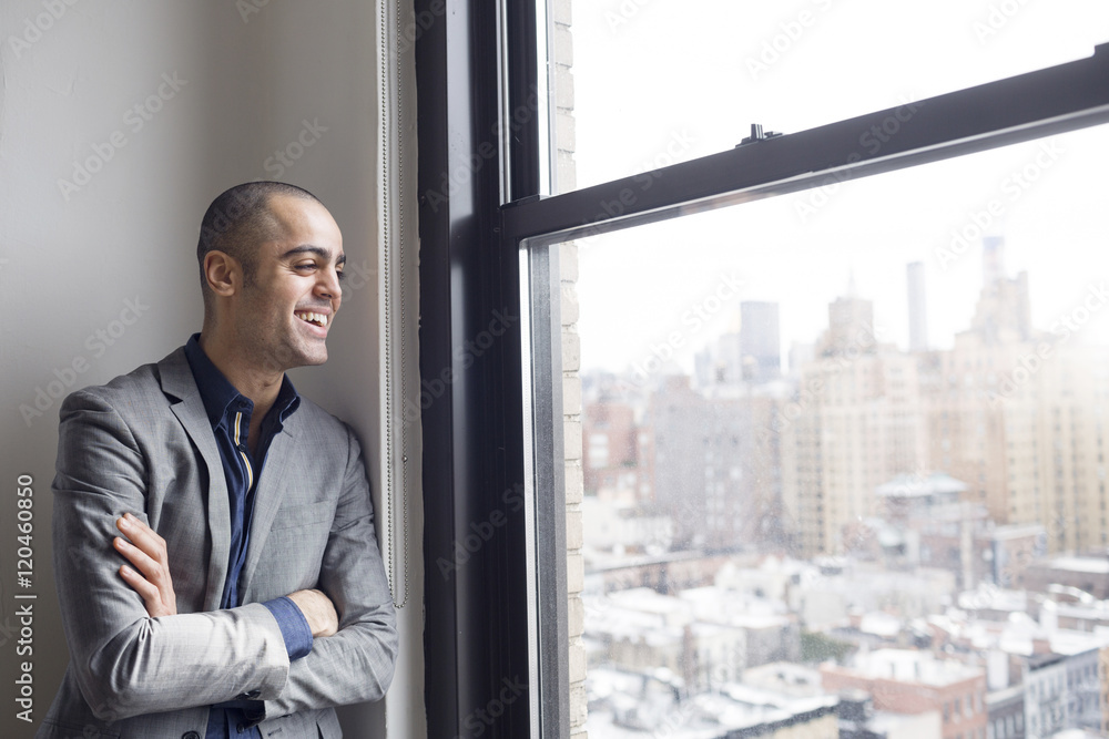 Happy businessman standing with arms crossed at glass window Happy businessman standing with arms crossed at glass window