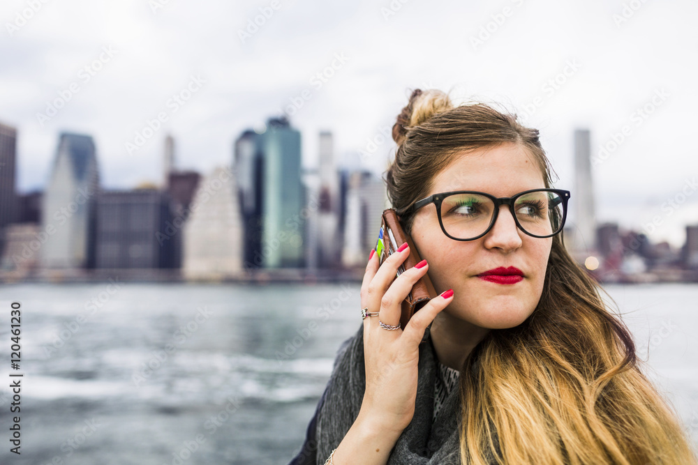Close-up of woman using phone while standing against East River in city Close-up of woman using phone while standing against East River in city