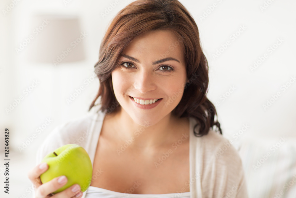 smiling young woman eating green apple at home smiling young woman eating green apple at home