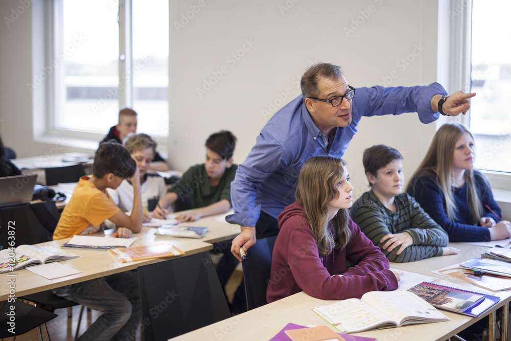 Teacher explaining schoolchildren (12-13) task in classroom Teacher explaining schoolchildren (12-13) task in classroom
