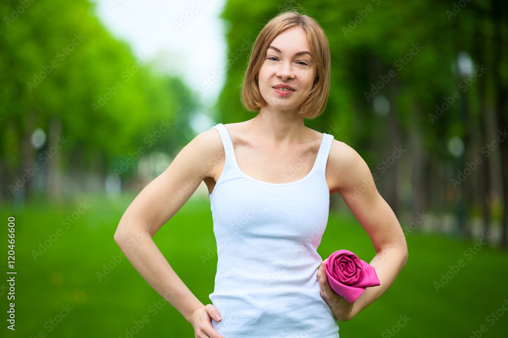 Fototapeta premium Portrait of happy fitness woman with yoga mat outdoors.