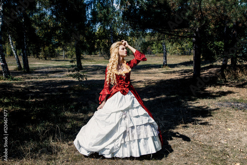 Blonde woman with long curly hair with flower accessory in antique red dress photo