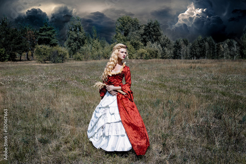 Blonde woman with long curly hair with flower accessory in antique red dress