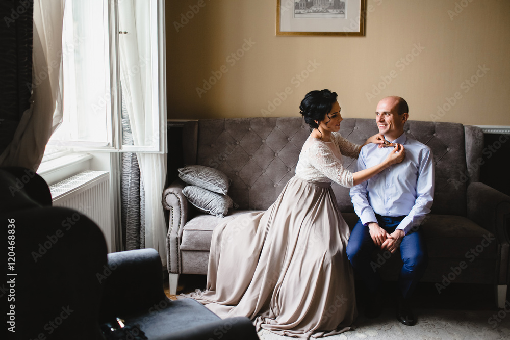 Beautiful luxury newlyweds sitting on the sofa in the room Beautiful luxury newlyweds sitting on the sofa in the room