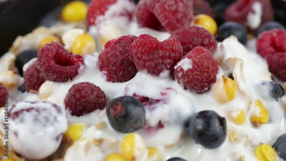 Cereal flakes with blueberries, raspberries and sea buckthorn rotating . Crunchy tasty muesli food background close-up. Cereals, berry and dried food mixed for breakfast . Cereal flakes with blueberries, raspberries and sea buckthorn rotating . Crunchy tasty muesli food background close-up. Cereals, berry and dried food mixed for breakfast .