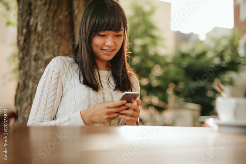 Woman using smart phone in a outdoor cafe.