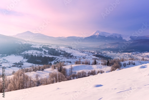 Amazing winter sunset over mountain snowy ridge, countryside landscape in soft pink light
