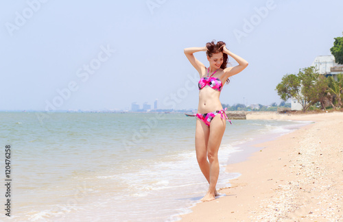 Beautiful women in bikinis strolling happily along the beach.